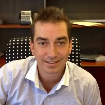 Professional man smiling in an office setting, representing business equipment solutions.