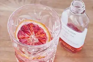 Vibrant pink grapefruit slice in a glass with ice and soda, close-up shot.