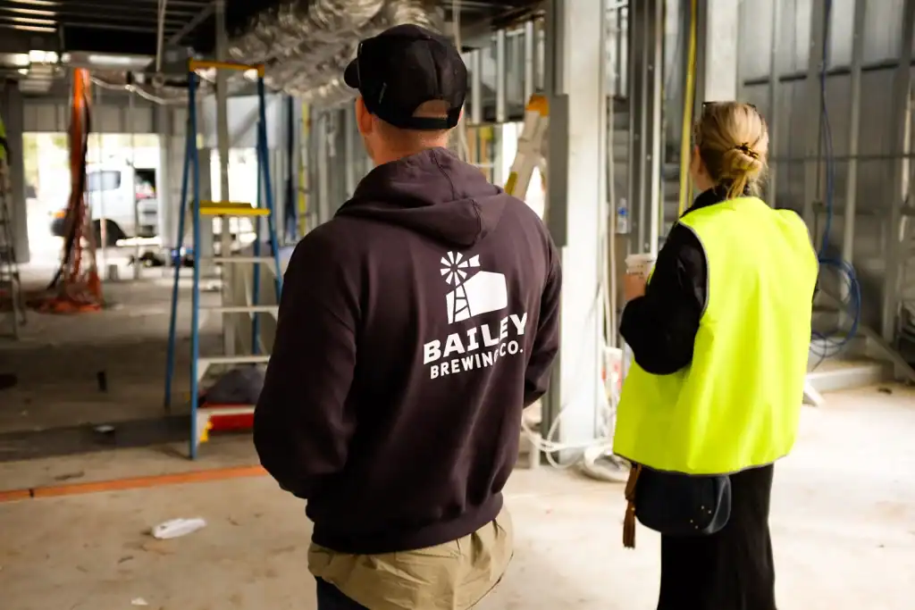 Bailey brewing company construction site workers in building under construction with metal framework and tools inside.