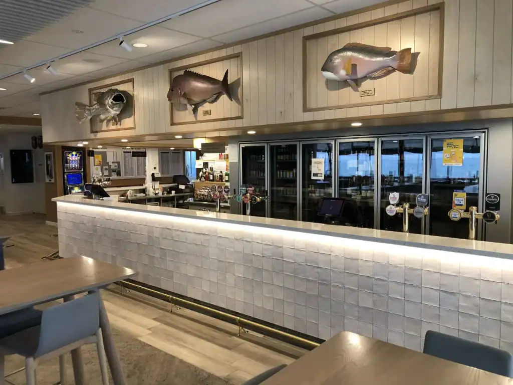 Fish trophies mounted on wood panels at a bar counter, modern hospitality decor, fish-themed wall art, stylish bar area in a restaurant or cafe, relevance.
