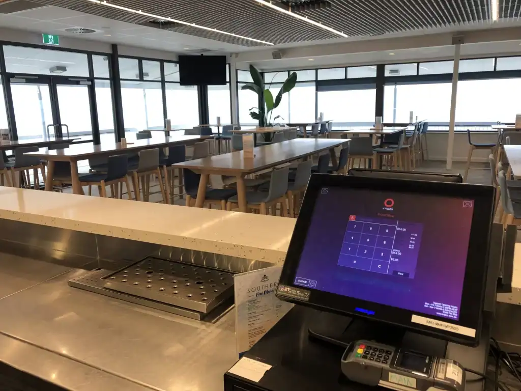 A modern cafe with electronic payment system and large windows providing natural light.