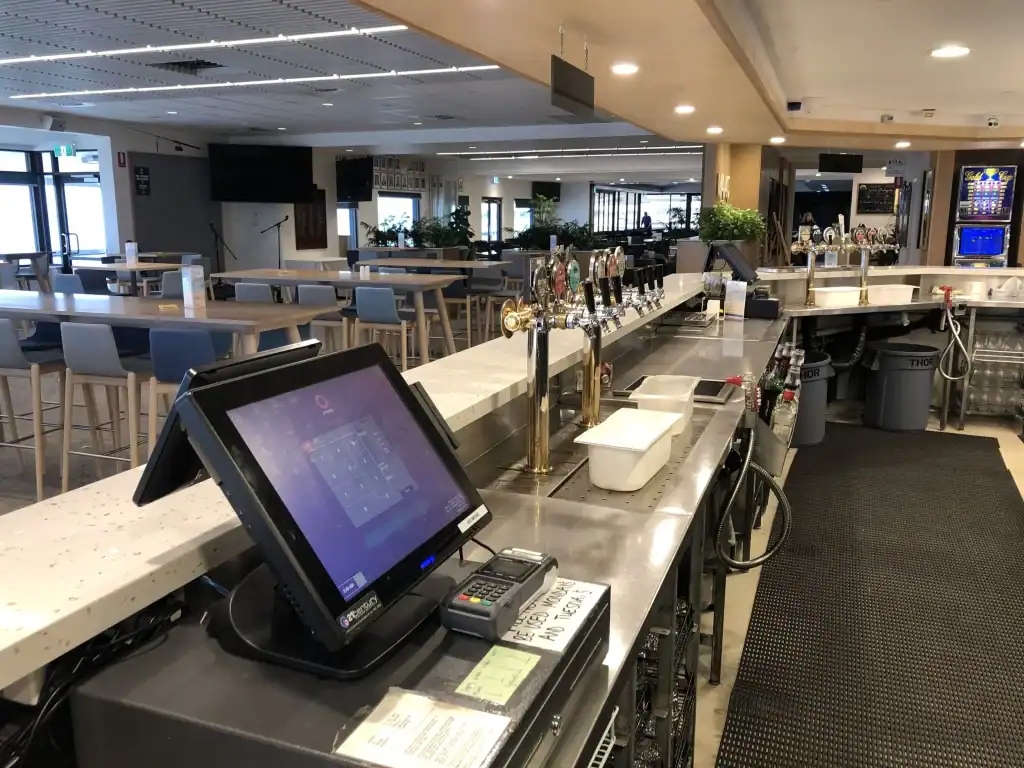 Modern bar with tap handles and a touchscreen point of sale system in a restaurant setting.