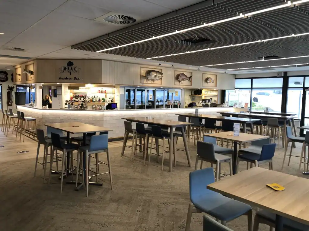 Modern bar interior with seating and large windows at a restaurant.