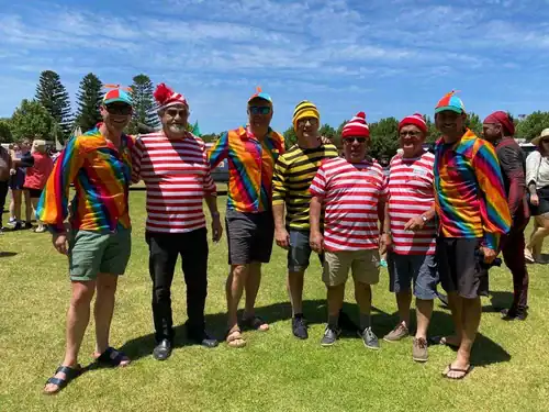 Brightly dressed people in colorful costumes enjoying an outdoor event on a sunny day.