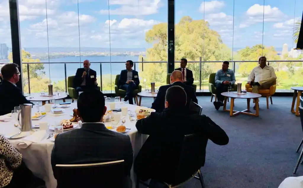 Boardroom meeting with strategic discussion overlooking river view and city skyline, business professionals engaged in upper-level corporate event.