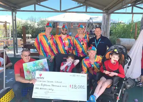 $18,001 donation check presentation at a colorful outdoor event.