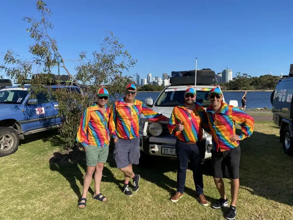 Colorful team wearing rainbow striped shirts and caps at an outdoor event.