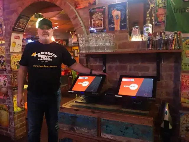 Digital point-of-sale touchscreen terminals in vibrant bar setting, ready for order processing.