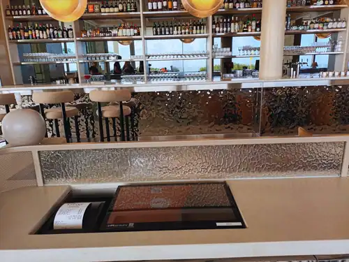 Modern office reception desk with integrated equipment and a bar area in the background.