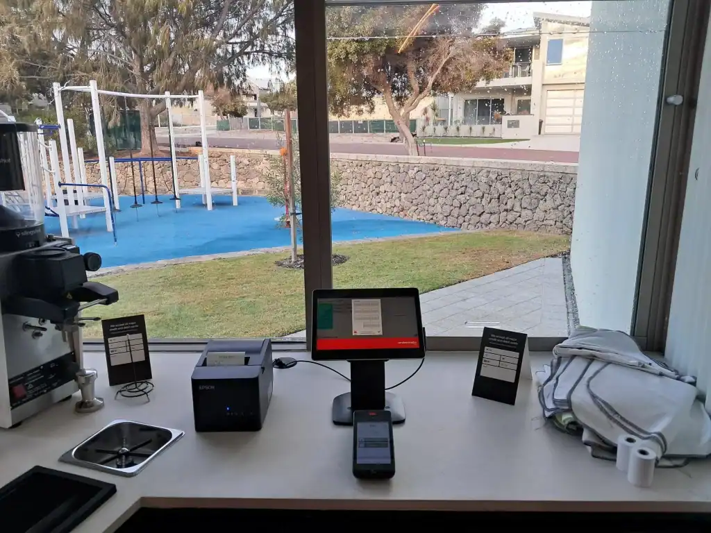 Printing and office equipment display at 21st Century Business Equipment, visible through a large window overlooking a playground and outdoor area.