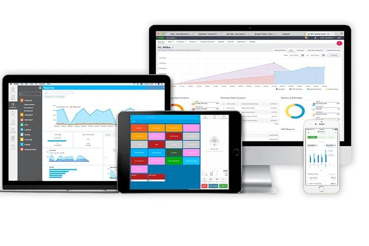 Laptop and tablets displaying business analytics and data management software, showcasing modern office technology.