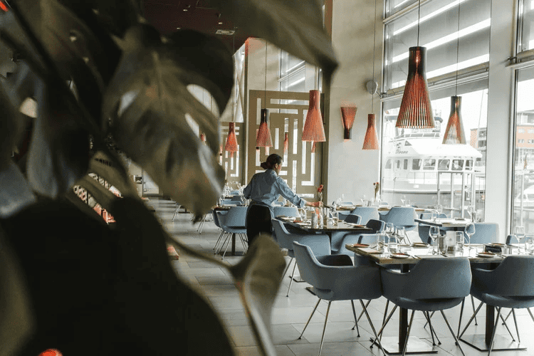 Modern restaurant interior with large windows, stylish pendant lighting, and comfortable seating.