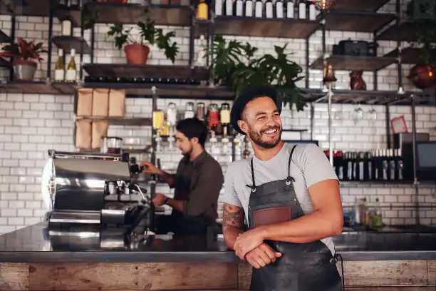 21st Century Business Equipment coffee shop barista smiling with professional coffee machines in a modern cafe setting.