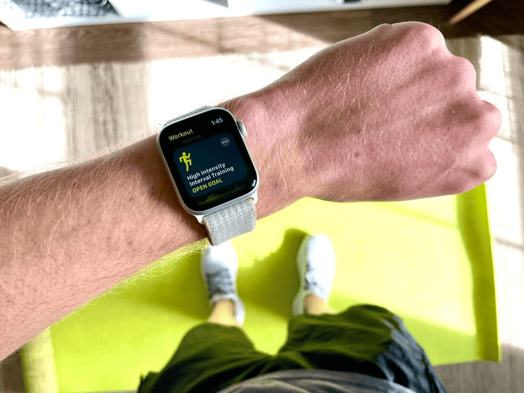 Smartwatch displaying workout goal, person exercising on a yoga mat, promoting fitness equipment and health tech.