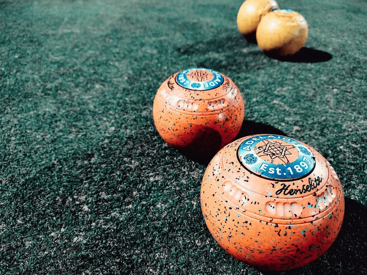 Yellow and orange bocce balls on artificial turf field, outdoor sport equipment, 21st Century Business Equipment.
