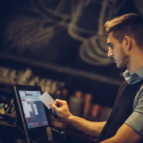 Professional man using POS touchscreen system in a cafe or restaurant.