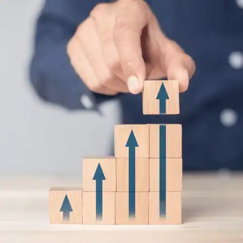 Increasing business growth with wooden blocks and upward arrows symbolizing success.