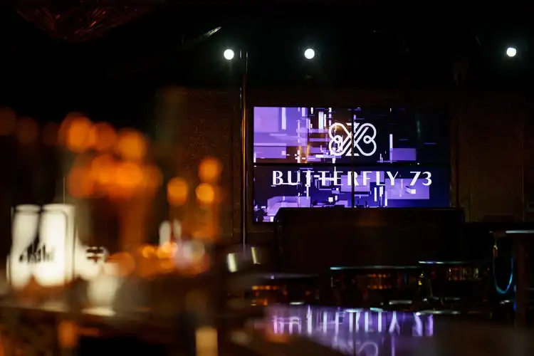 Butterfly logo displayed on large digital screen in modern venue setting.
