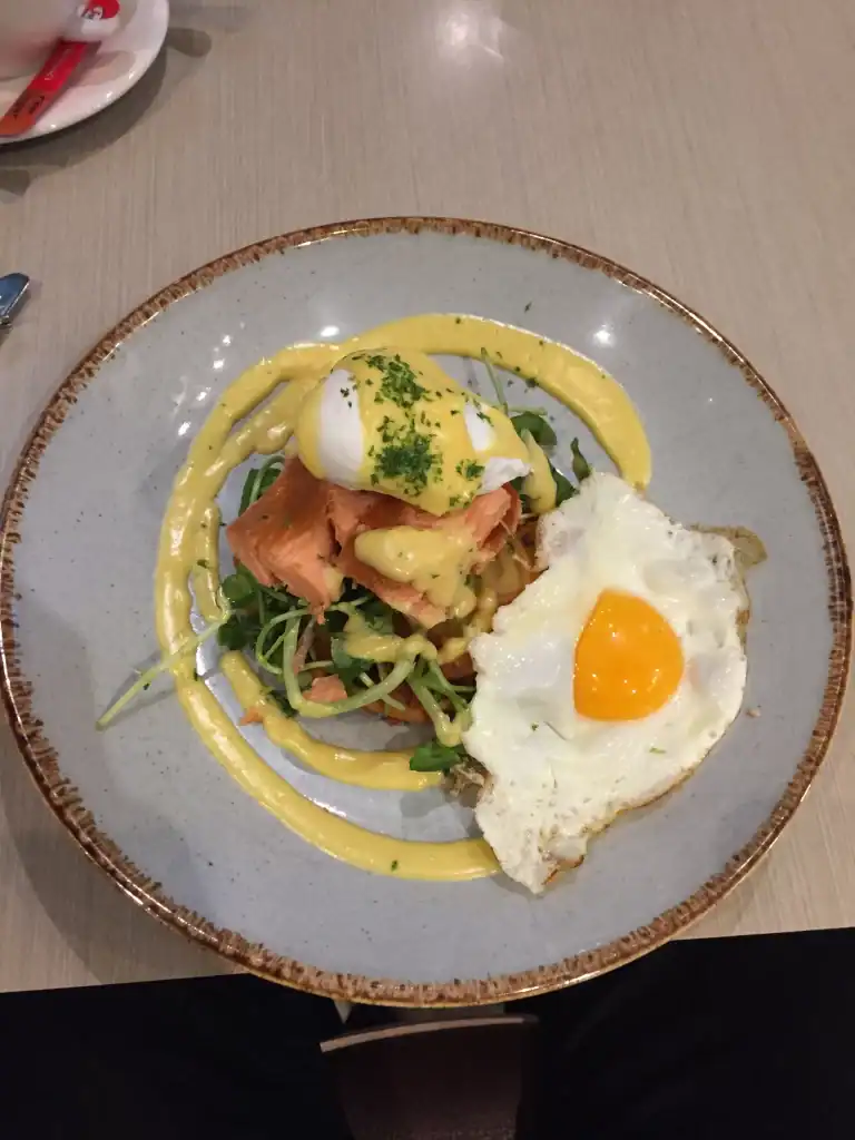 Salmon salad with poached egg and yellow sauce on a ceramic plate.