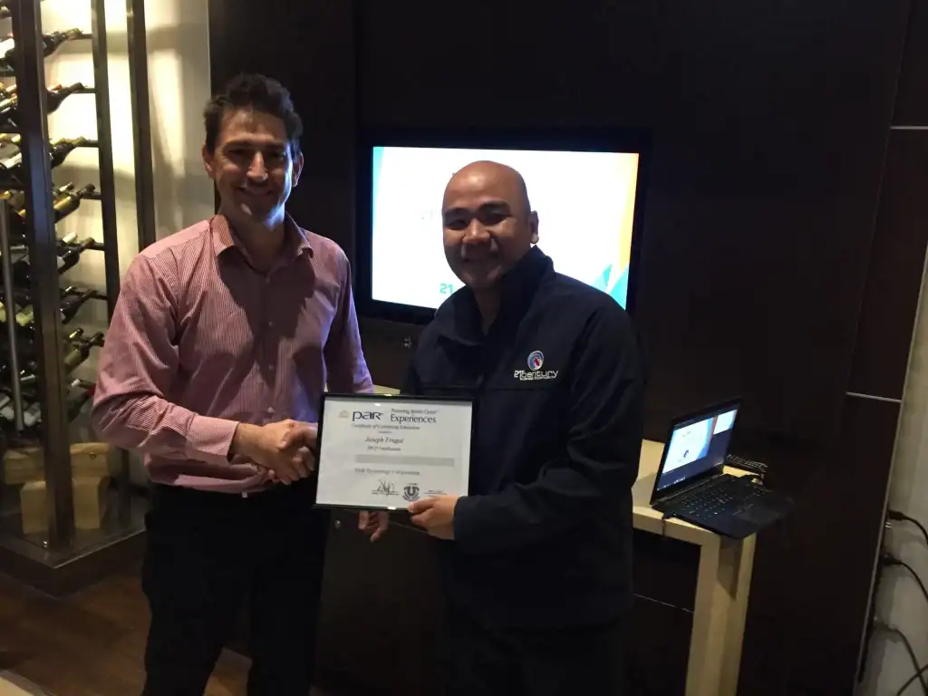 Certificate presentation at 21st Century Business Equipment featuring two smiling men shaking hands in a modern office setting.