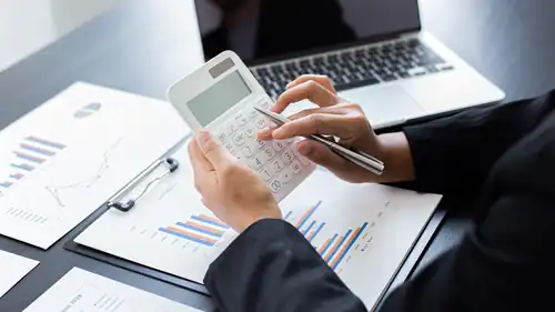 Calculate business expenses with calculator and financial documents on desk, business analysis and accounting concept.