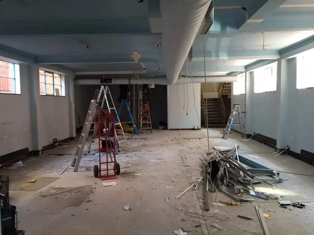 Renovation of office space with construction workers installing ceiling and electrical systems.