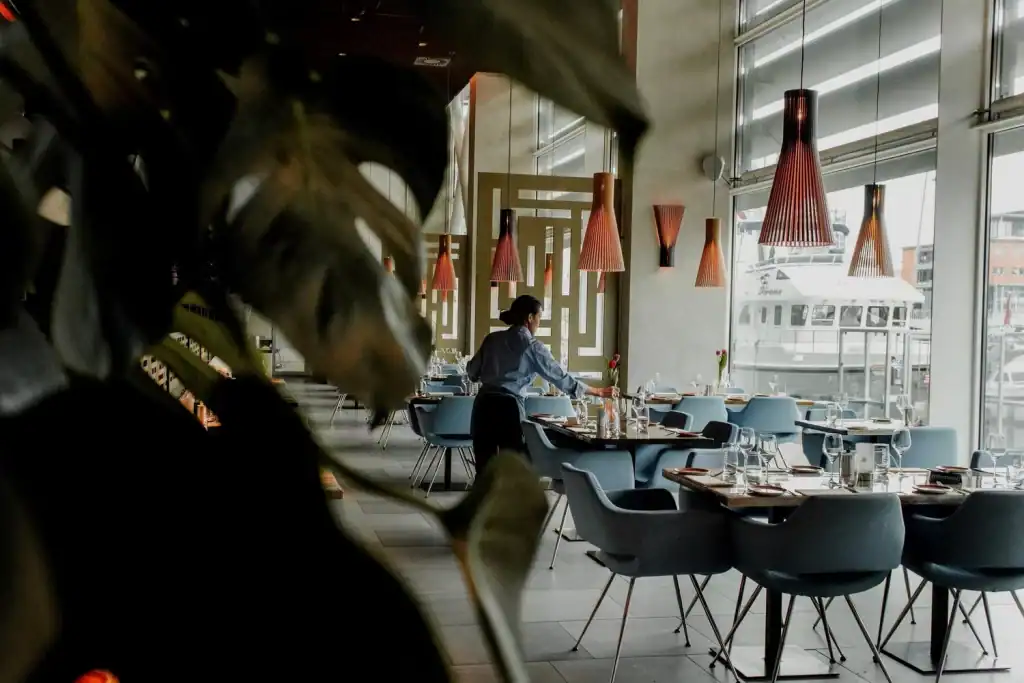 Modern restaurant interior with large windows, contemporary lighting, and stylish dining setup for guests.
