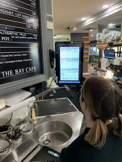 Menu display and digital ordering system at a cafe counter.