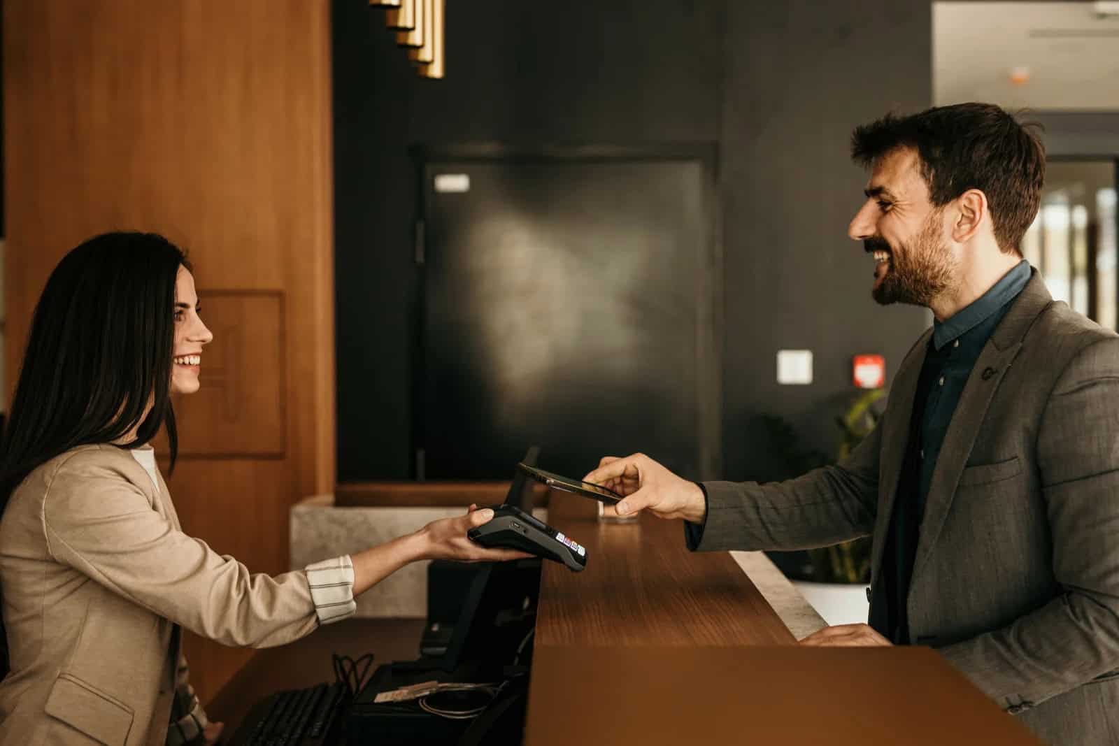 Modern business professional exchanging payment at hotel reception desk.